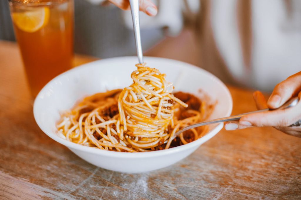 A close-up of a delicious spaghetti meal being served elegantly with a fork and spoon.