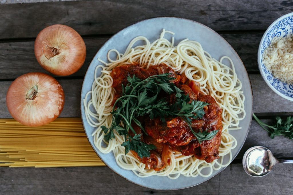 Flatlay of spaghetti pasta with rich tomato sauce on a wooden table.